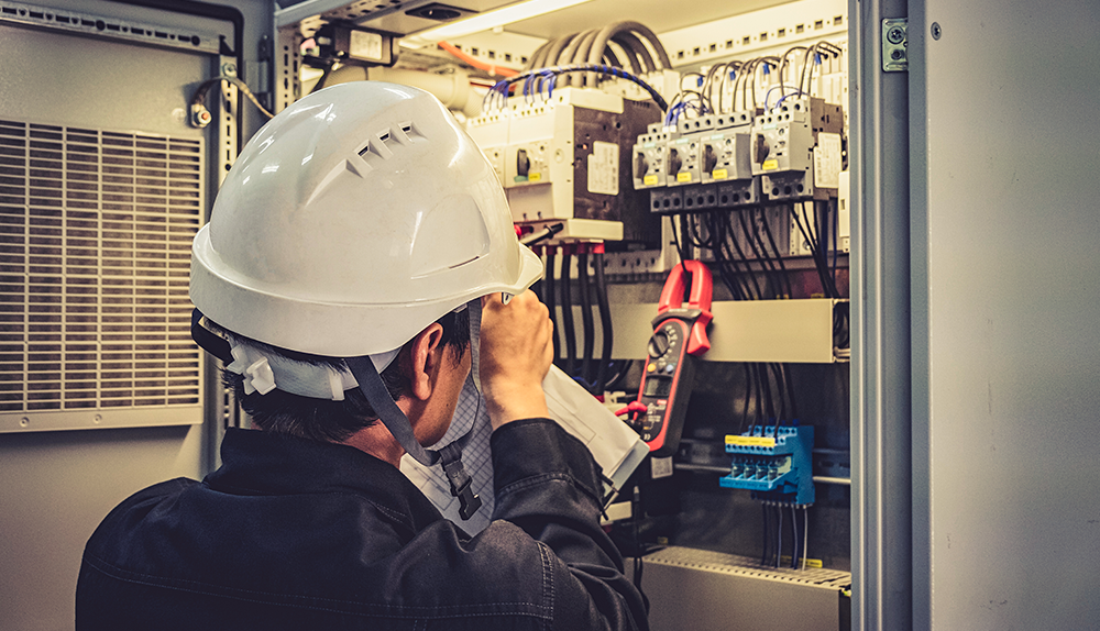 AES Maintenance engineer in a hard-hat testing HVAC equipment